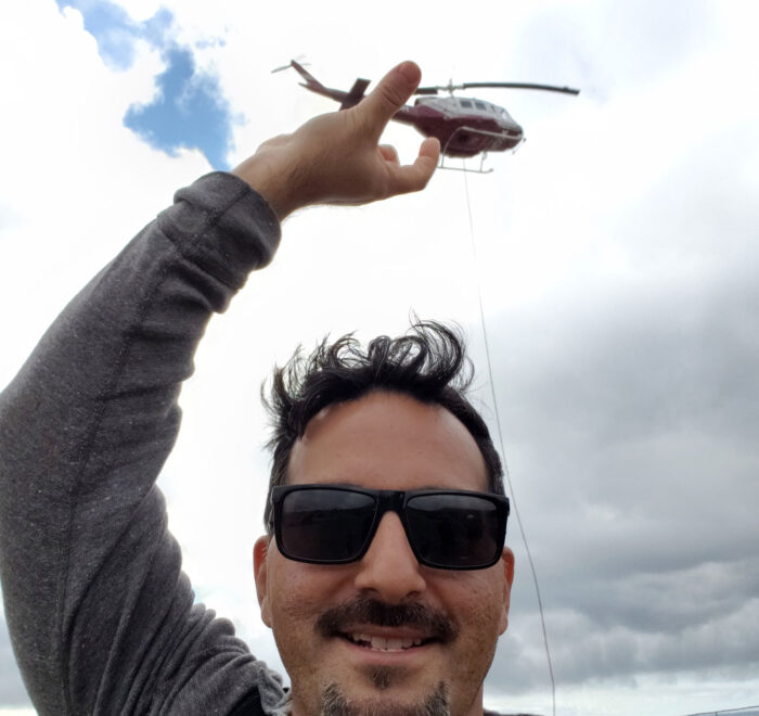 Man wearing sunglass behind a flying helicopter