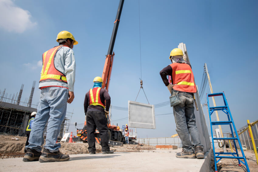 A crew of construction workers surveying a precast concrete installation.