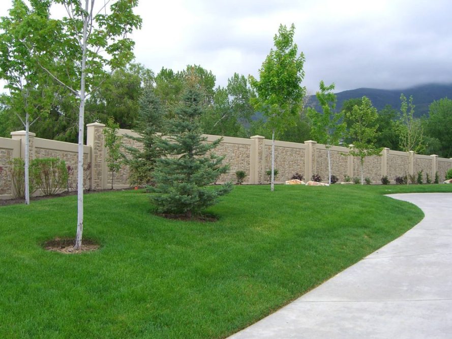 Residential precast concrete perimiter wall surrounded by lush green landscape.